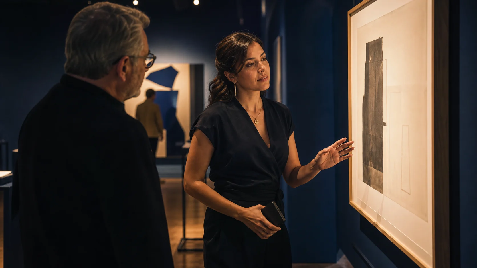 A fictional woman named Gabriela thoughtfully considering an artwork beside a collector she trusts.